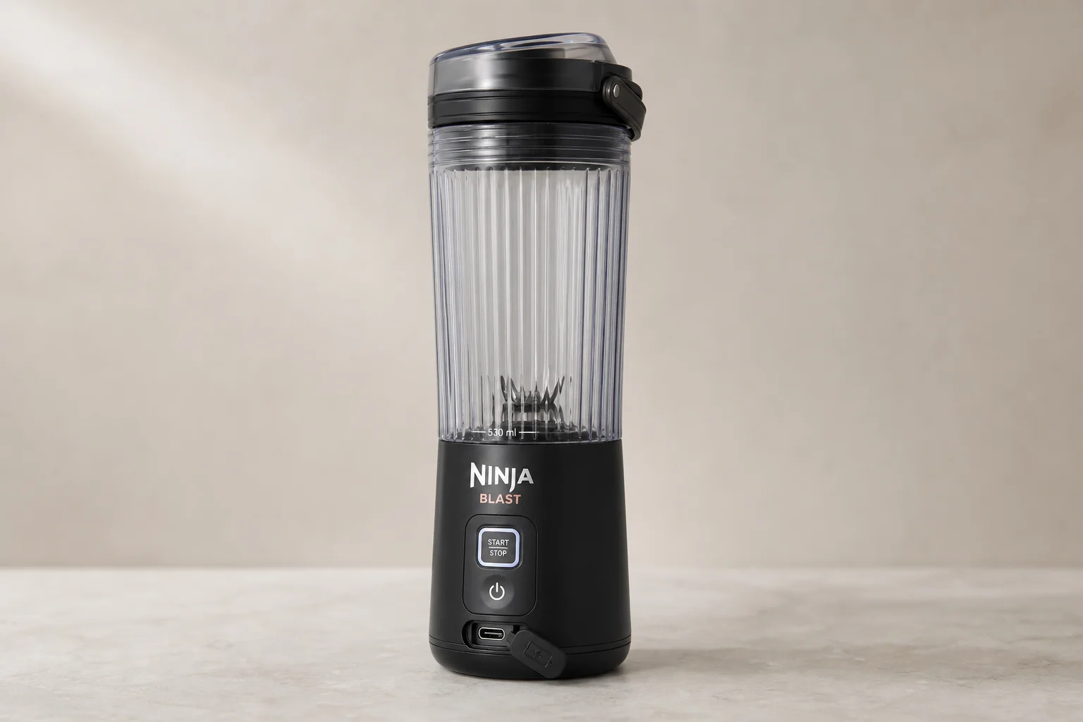 Tre frullatori portatili allineati su una superficie in cemento: Ninja Blast, NutriBullet e Fridja