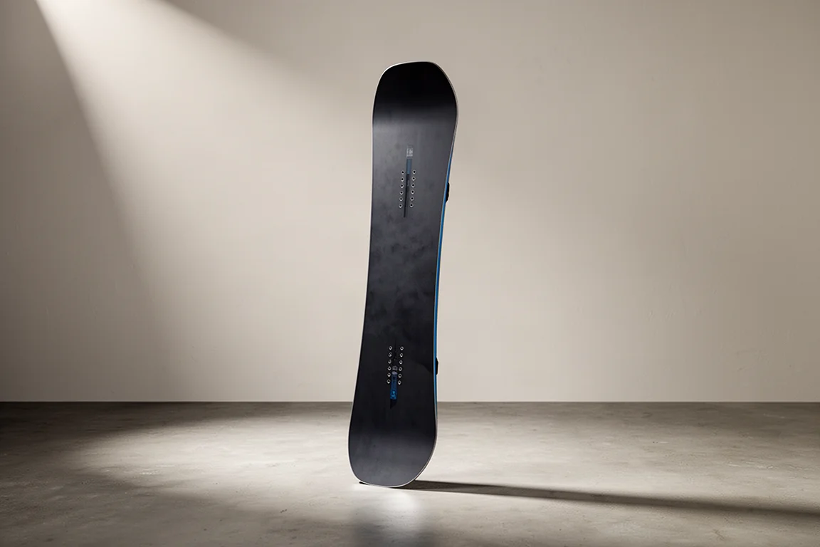 Prancha de snowboard freeride direcional com camber tradicional apoiada em um piso de concreto