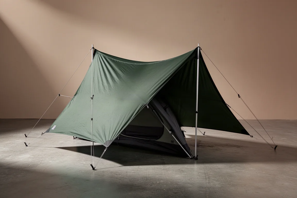 Low-profile green solo backpacking tent with four-pole frame on a concrete surface