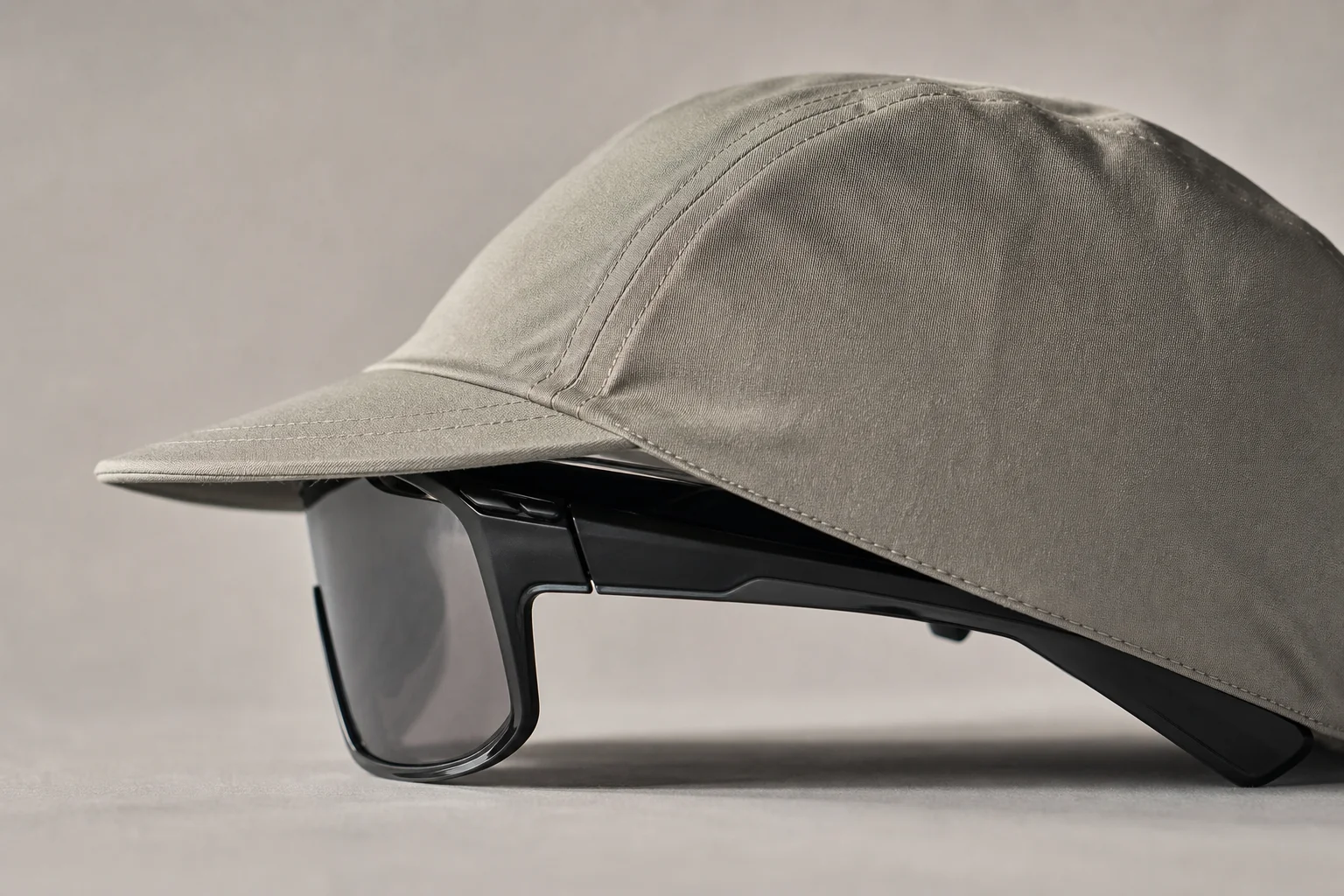 Occhiali sportivi indossati sotto un cappellino da ciclismo con visiera curva per mostrare la calzata delle aste
