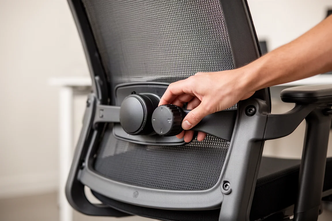 Primer plano de una mano ajustando el soporte lumbar en una silla de oficina moderna