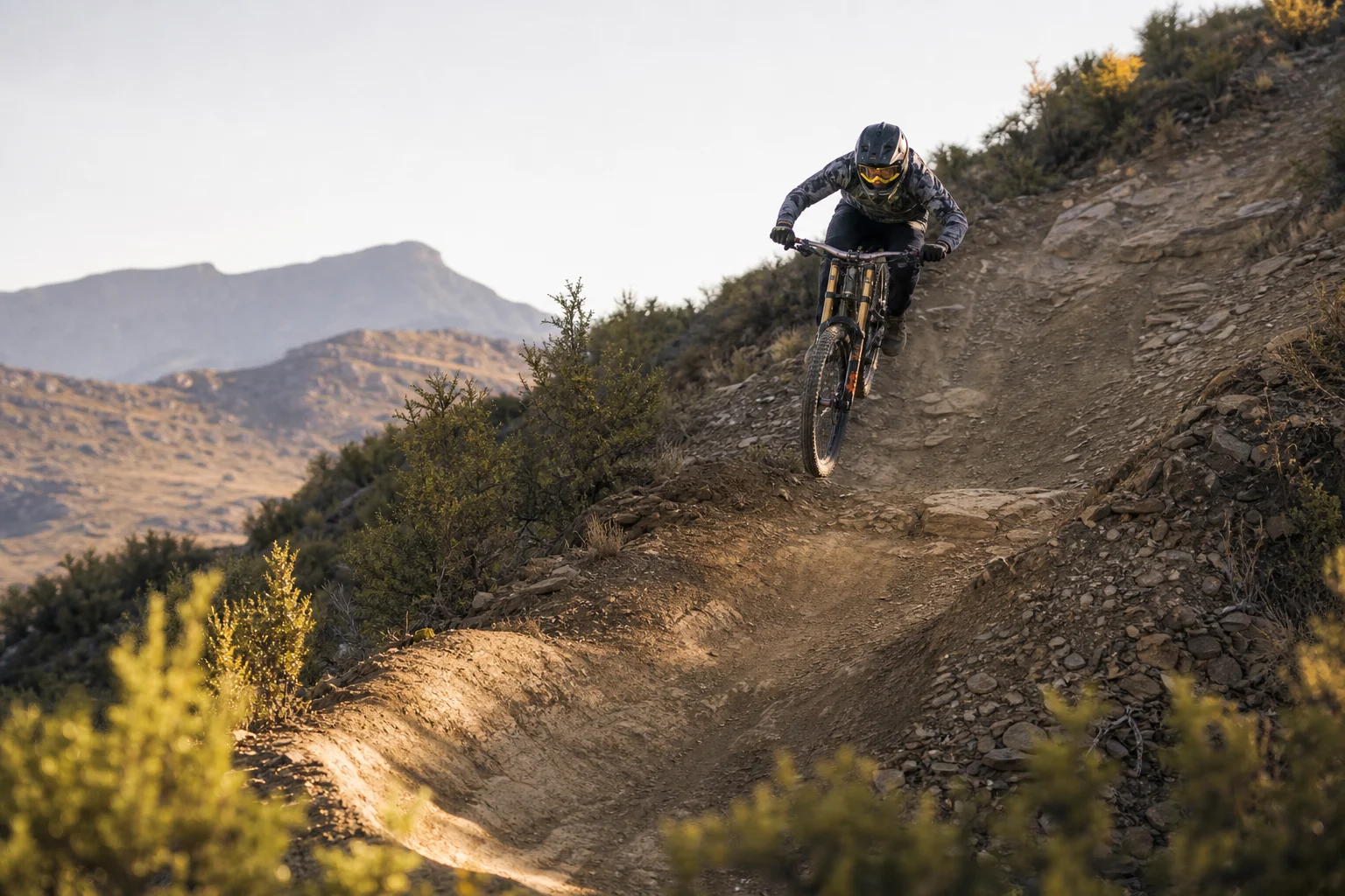 Mountainbiker bei der Abfahrt auf einem steilen Downhill-Trail mit technischen Elementen