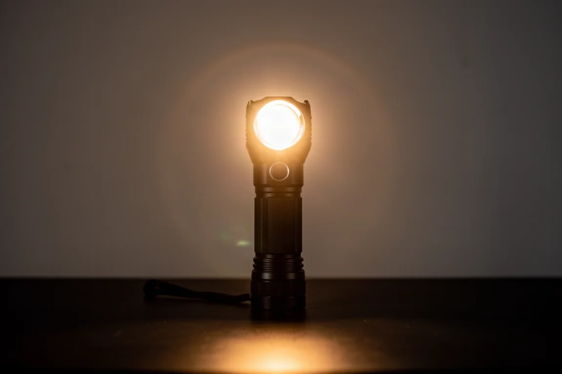 Ficklampa som kastar ett varmt bakåtriktat ljus mot kameran på en mörk stig