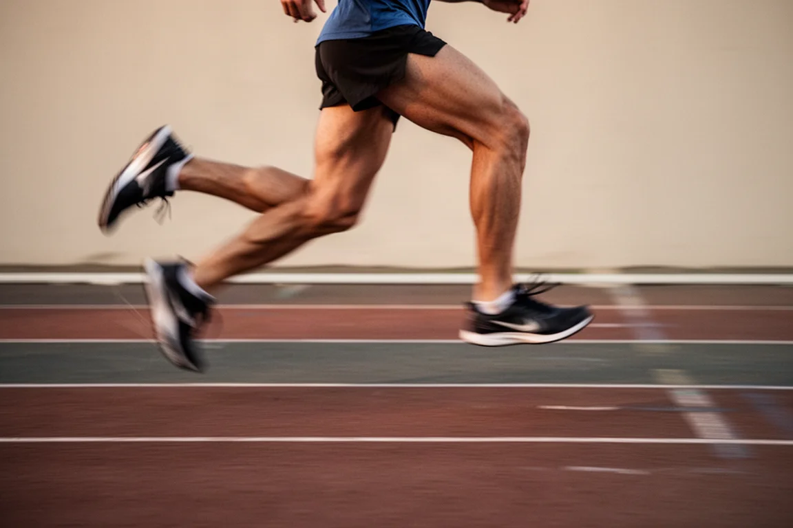 Runner doing interval reps on an athletics track in early evening light