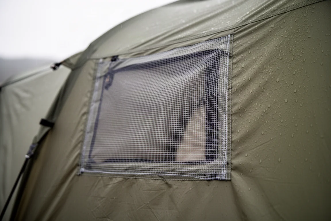 Close-up of a large mesh vent panel on tent fabric with water beading on the outer shell