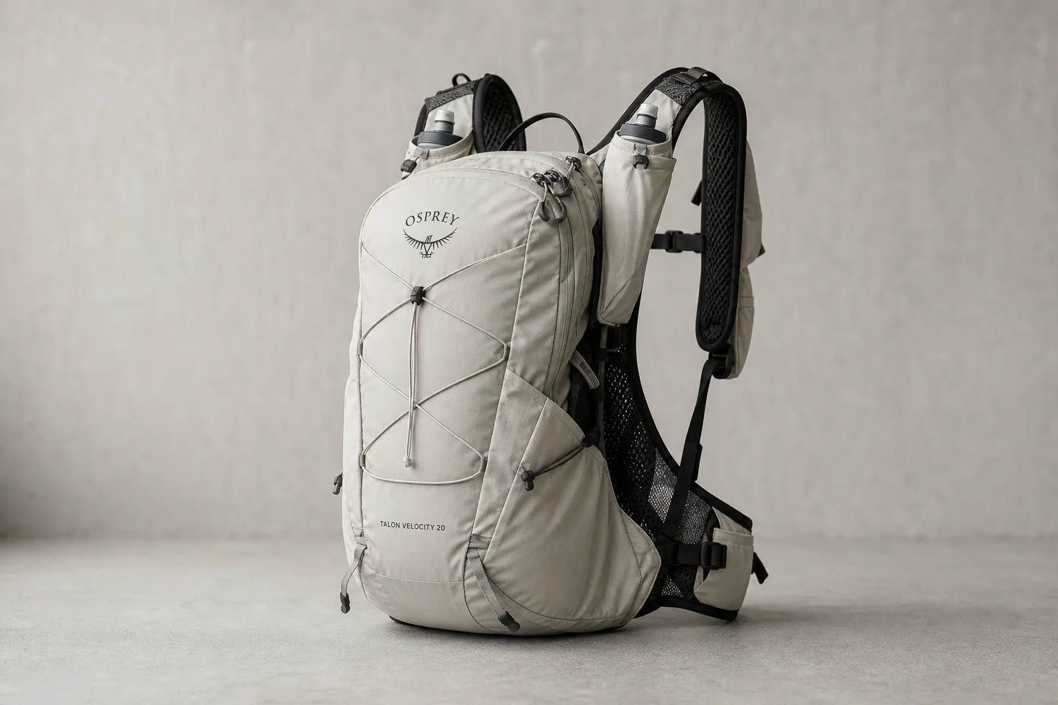 Mochila Osprey Talon Velocity 20 exibida em uma superfície de concreto mostrando bolsos frontais e alças de ombro