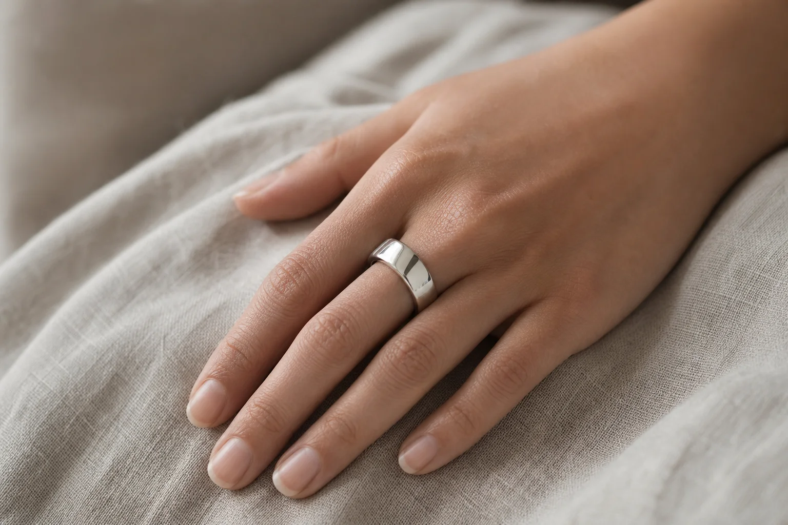 Close-up of a shiny silver Oura Ring 5 worn on a finger with natural skin tone