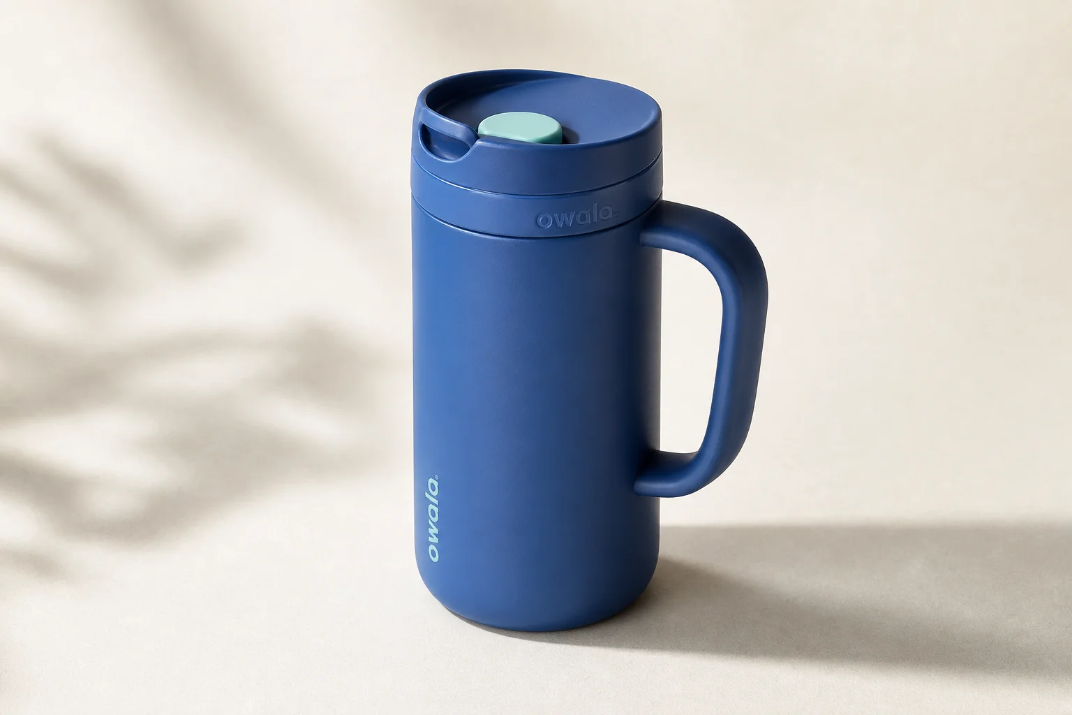 Nine insulated travel mugs arranged on concrete surface in various styles and colors