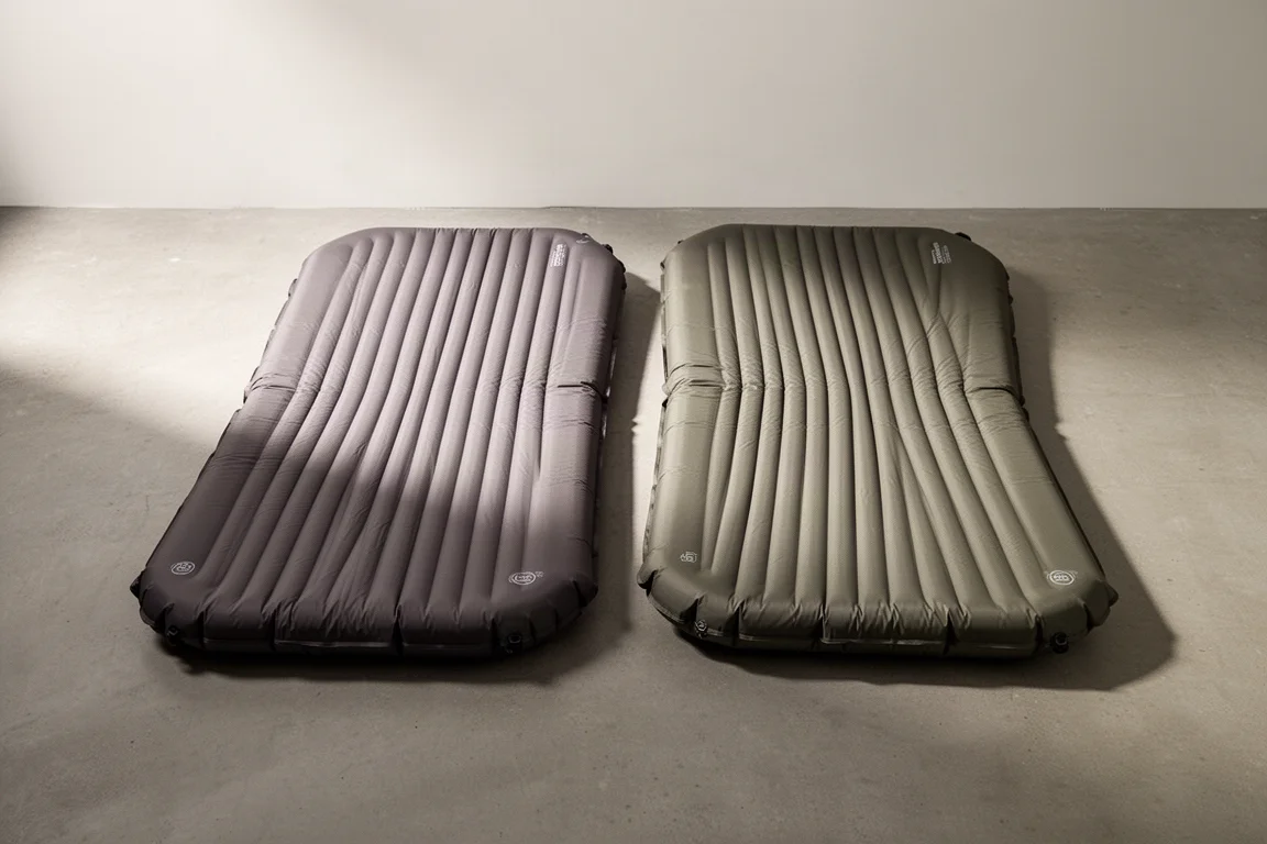 Two insulated backpacking sleeping pads with quilted baffles side by side on concrete