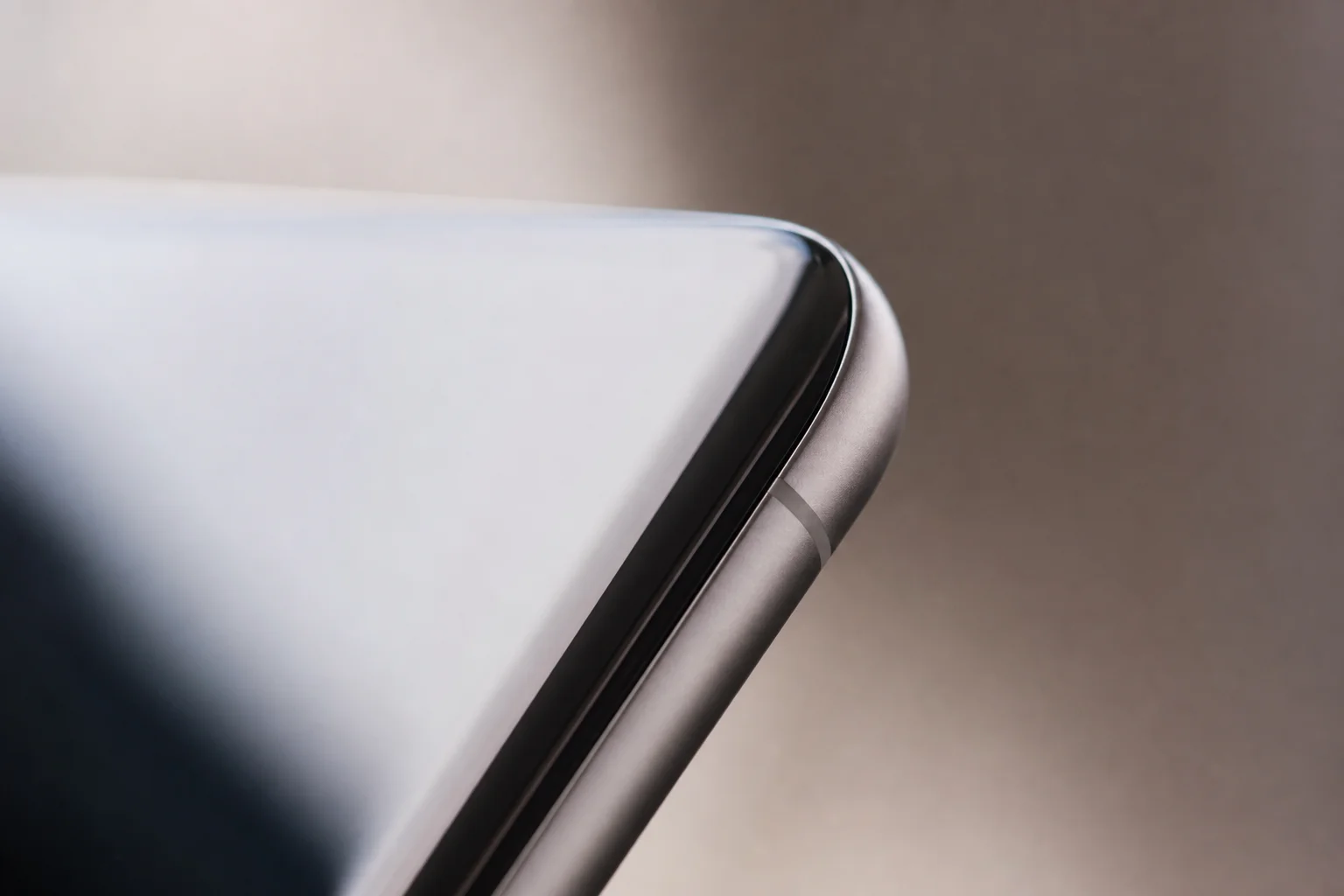 Nahaufnahme der gewölbten Displaykante eines Smartphones bei sanfter Beleuchtung