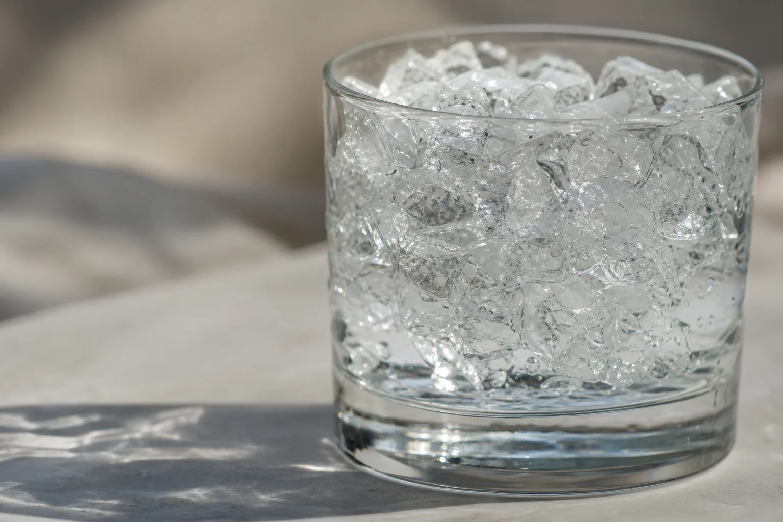 Ghiaccio tritato in un bicchiere con acqua e luce che rifrange attraverso i cristalli