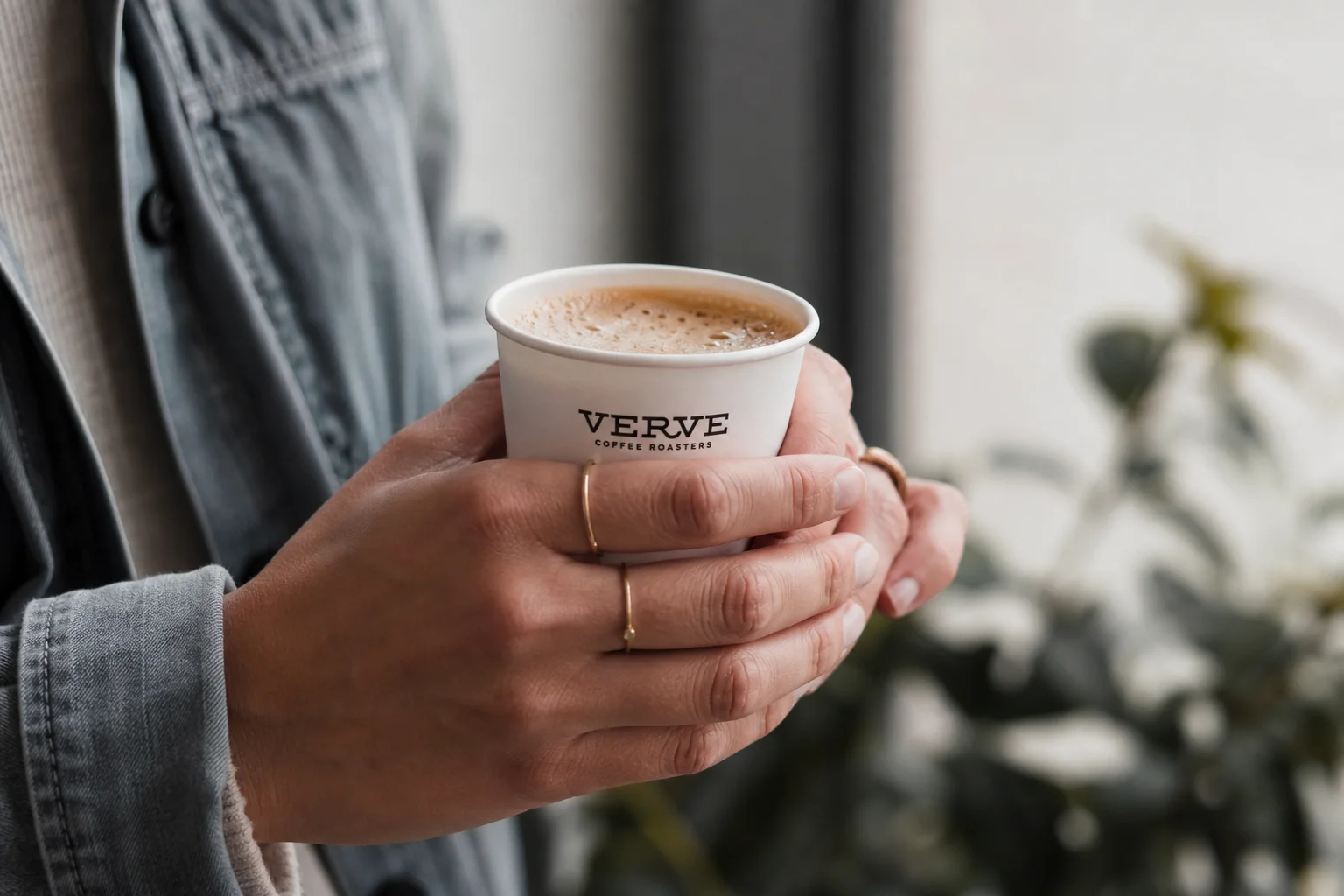 Hands holding a small paper cup during coffee tasting