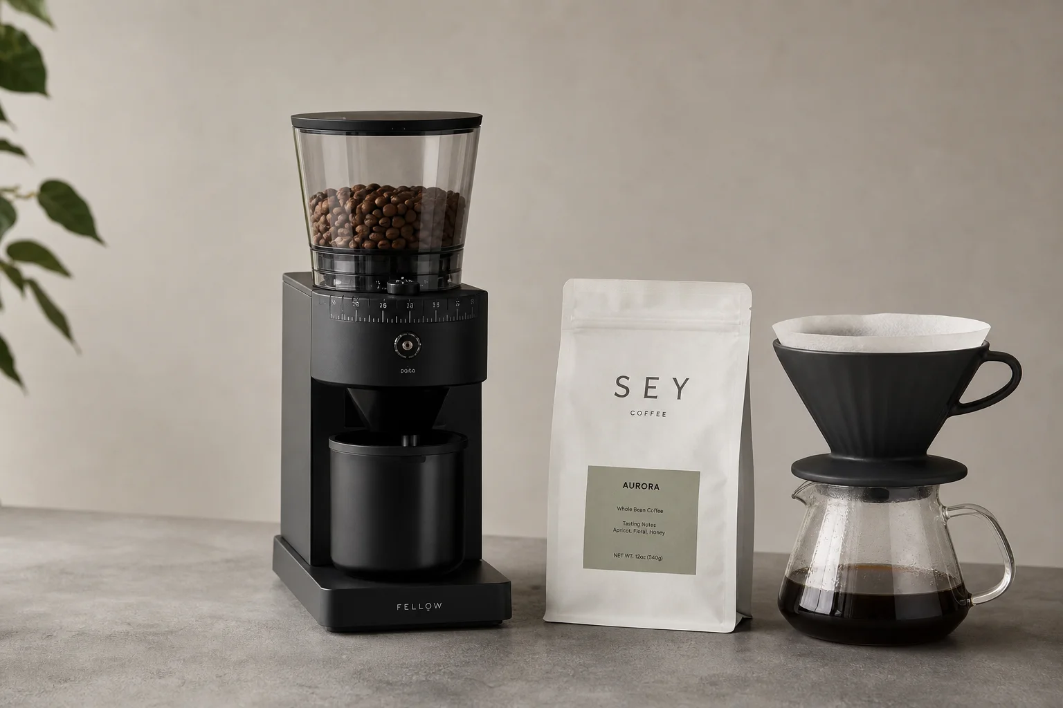 Premium burr grinder, specialty coffee bag, and pour-over dripper on concrete surface