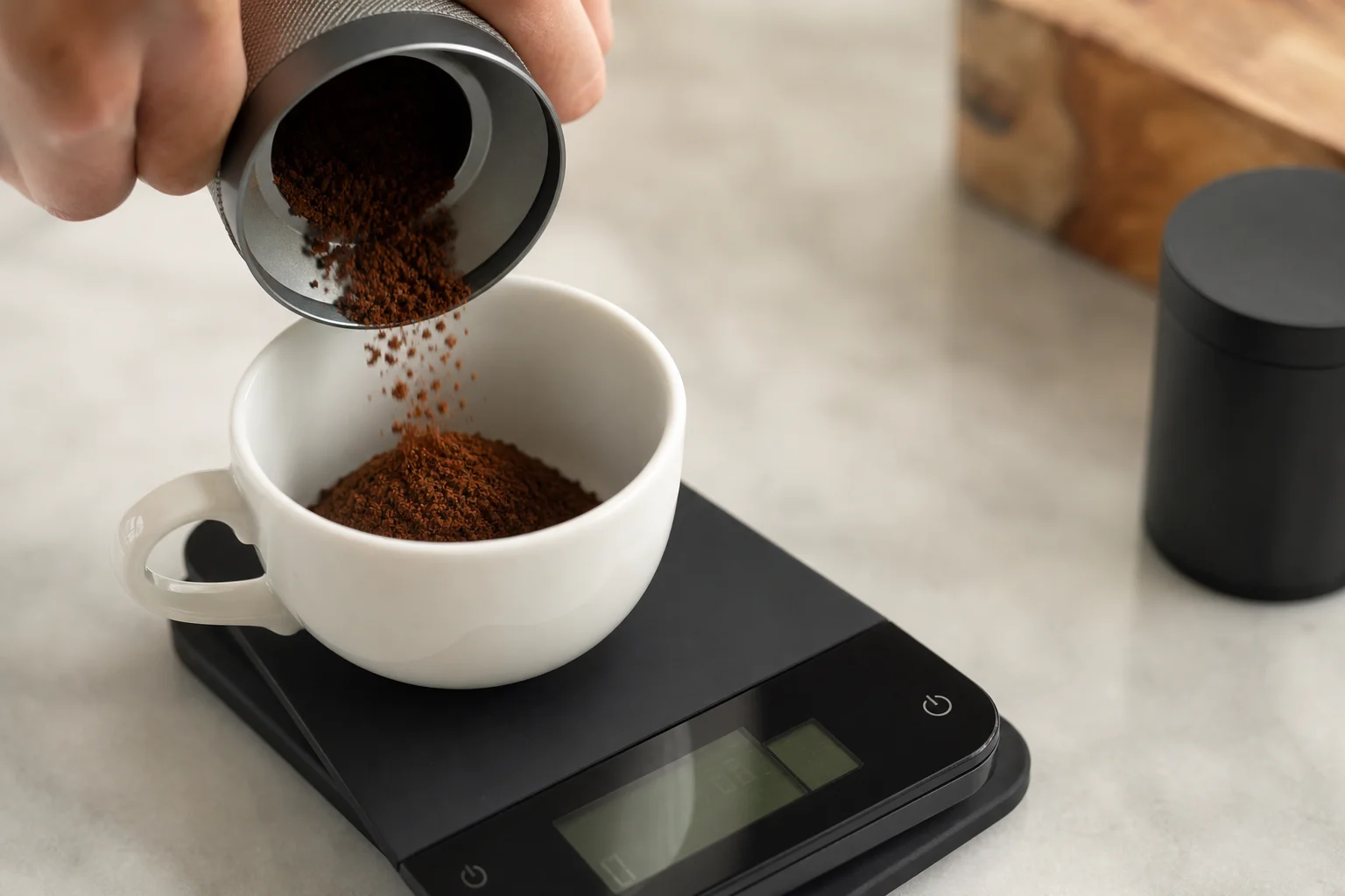 Kaffee wird in einer weißen Espressotasse auf einer digitalen Waage abgewogen