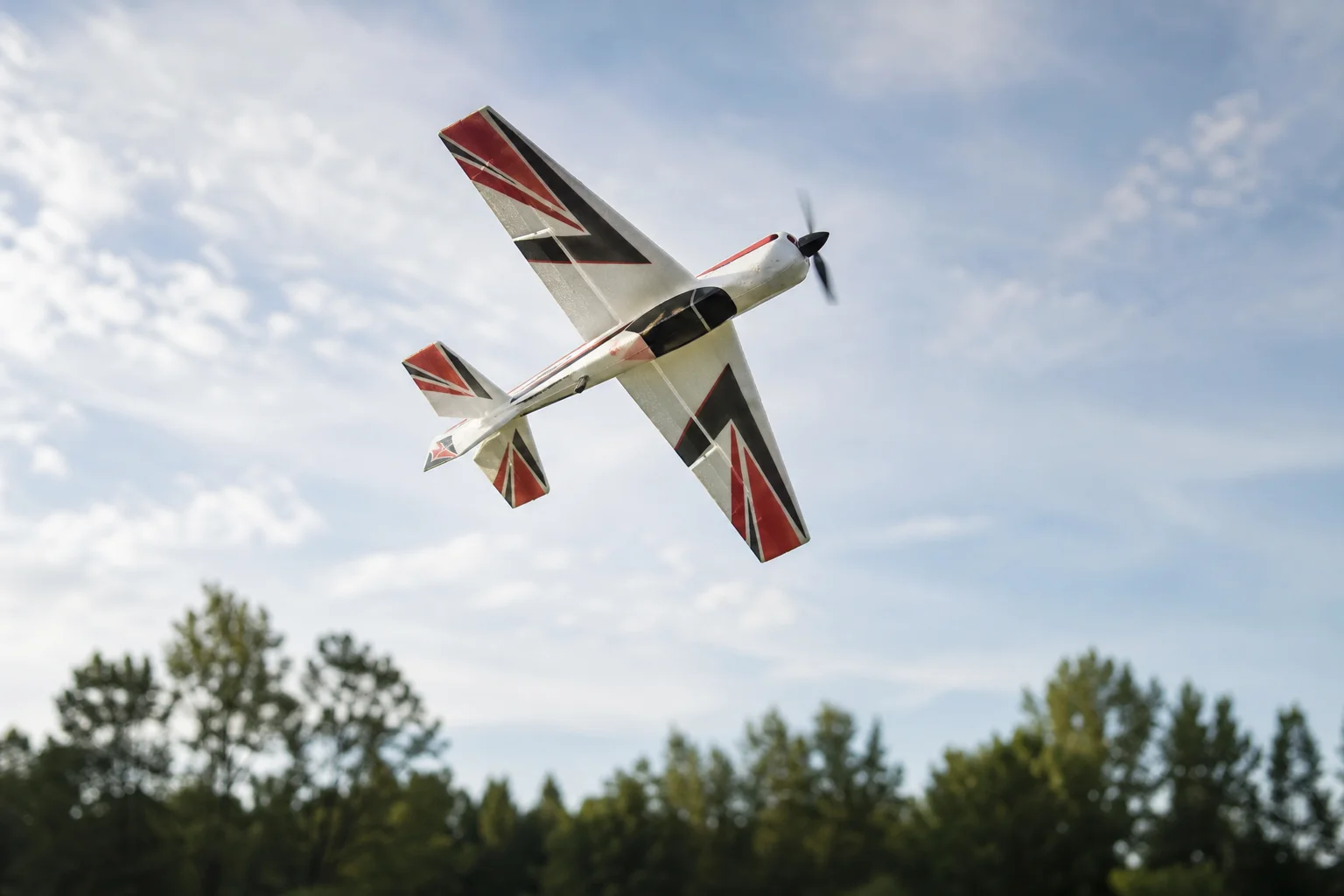 Schaumstoff-RC-Flugzeug bei einem Kunstflugmanöver vor Bäumen
