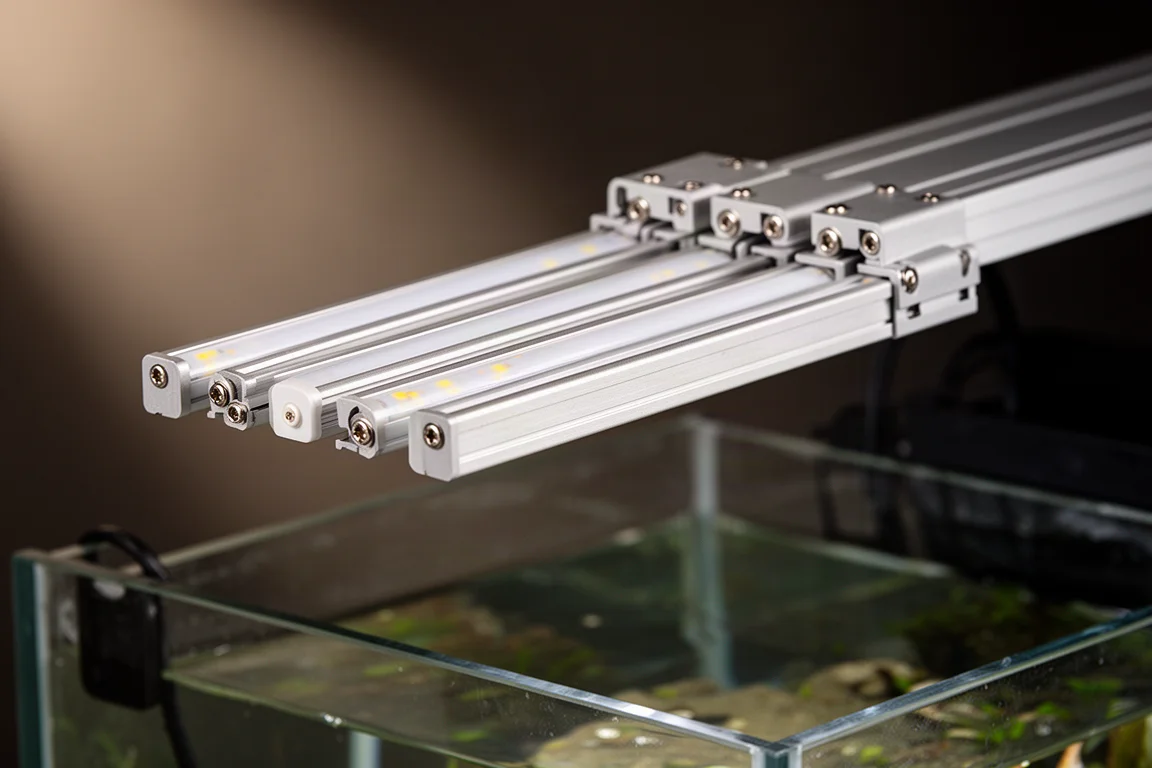 Flera smala LED-strips vinklade inuti ett fäste ovanför ett revakvarium