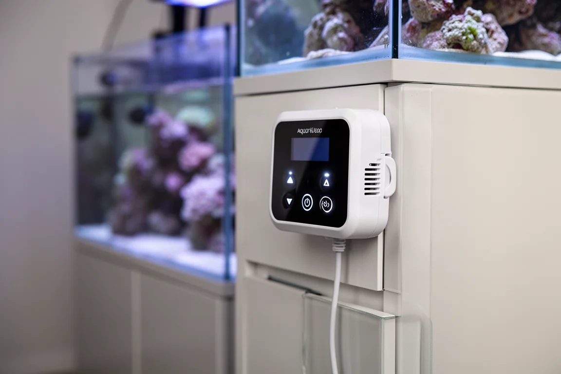 White aquarium pump controller with touch panel and LCD screen mounted on a cabinet