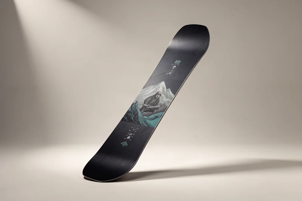 Directional snowboard standing at an angle on a neutral grey backdrop