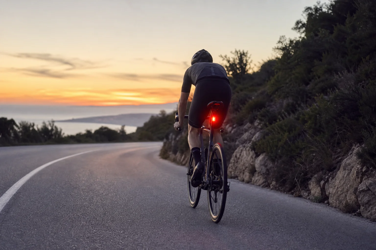 Cyclist braking on road with rear light glowing brighter in response to deceleration