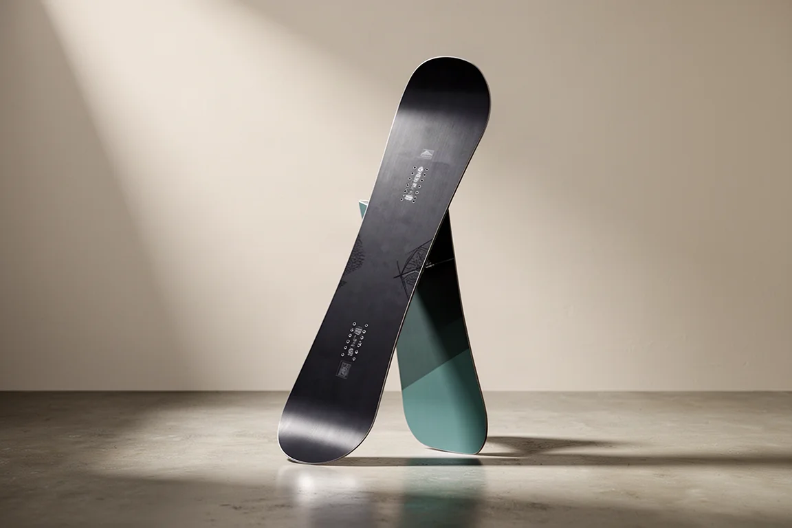 Twin-tip camber snowboard standing upright on a polished concrete floor in studio light