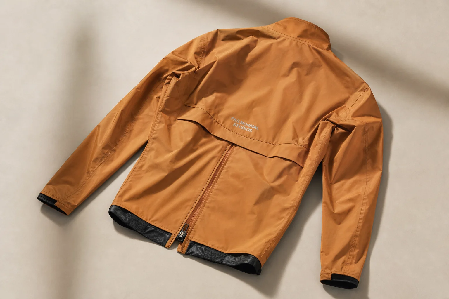 Cinq vestes de pluie pour le cyclisme de différentes couleurs disposées sur un fond neutre
