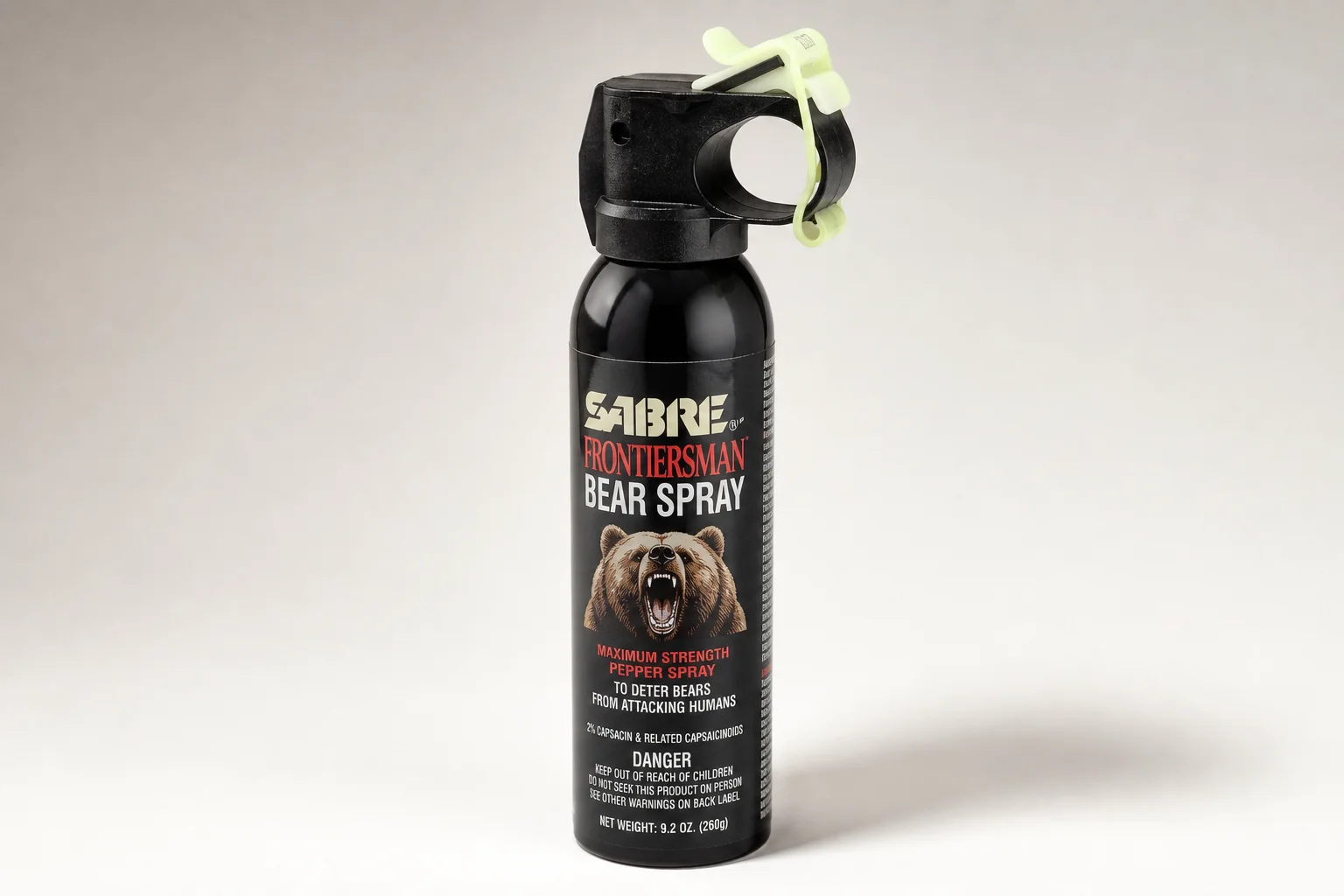 Five bear spray cans of varying sizes arranged on concrete surface