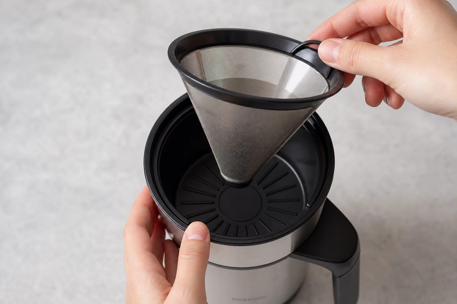 Hands adjusting the brew basket cone filter inside the machine