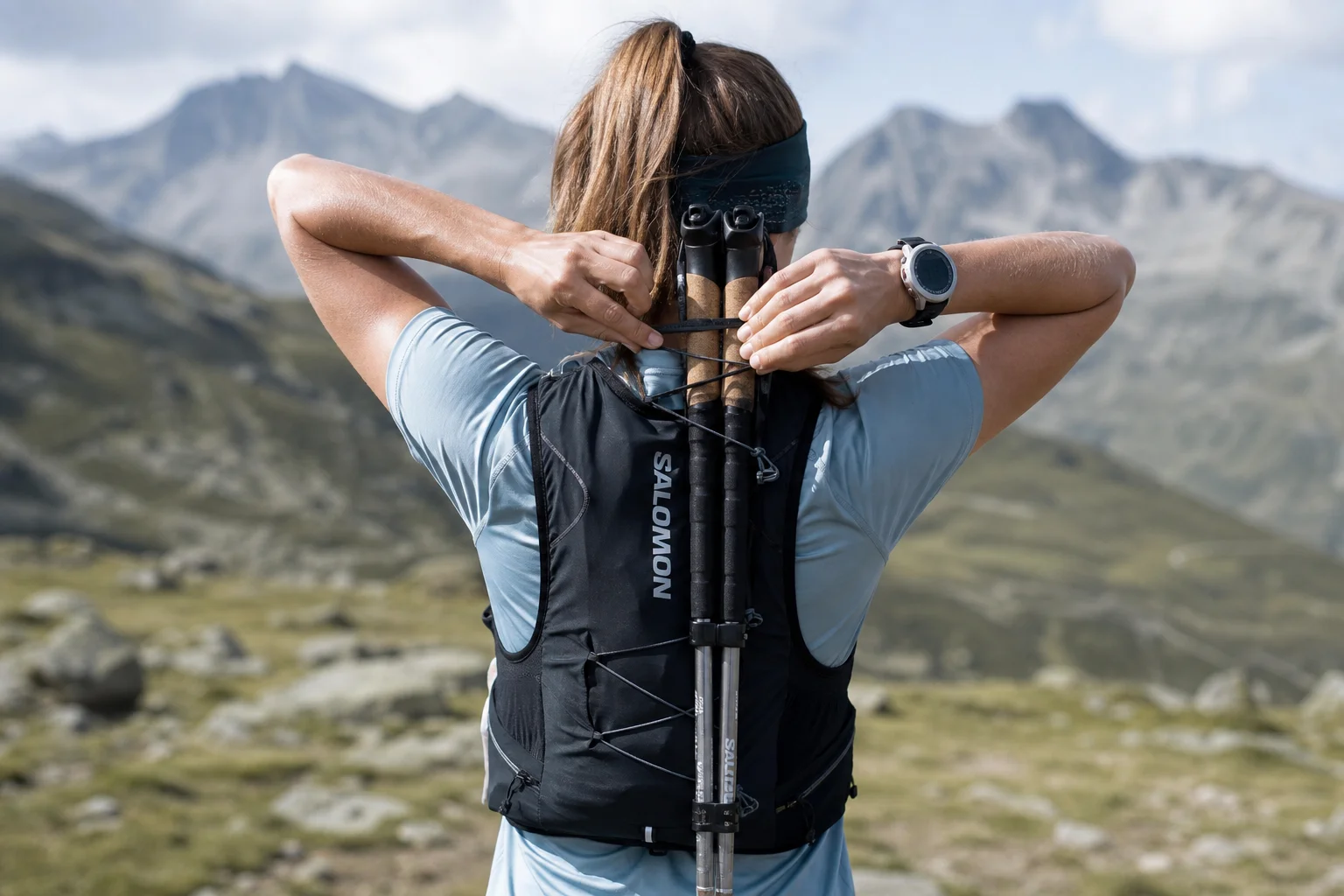 Corredor de trail ajustando los bastones de trekking sujetos al chaleco de running
