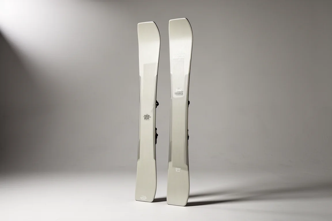 Pair of wide freeride skis standing upright against a grey backdrop