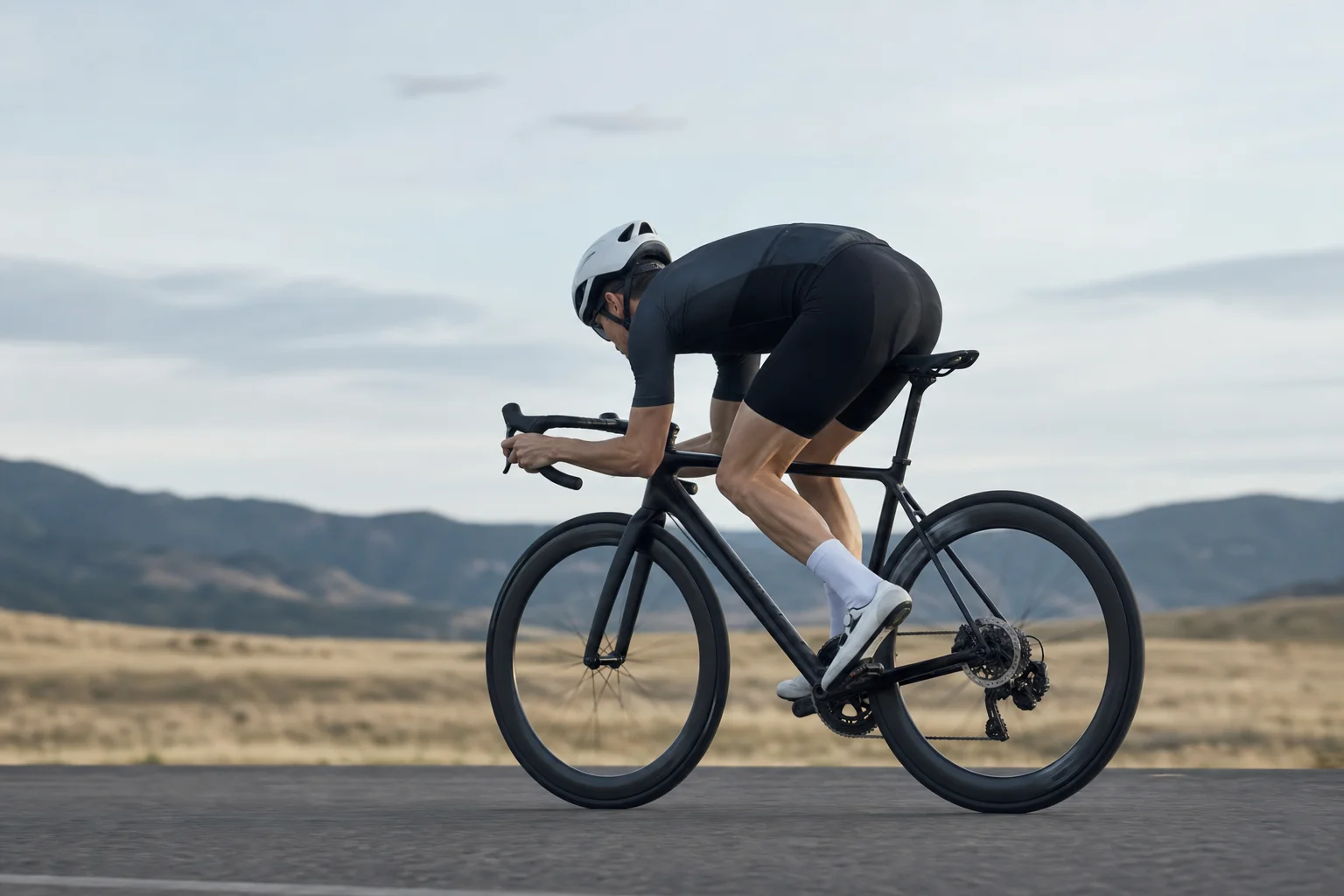 Road cyclist in aerodynamic position on a flat open road