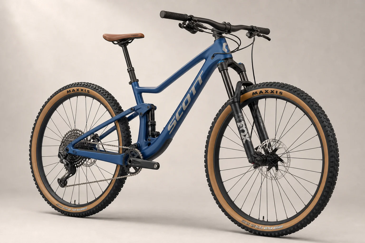 Bicicleta de montaña Scott Spark 970 con cuadro azul y neumáticos de flanco color canela sobre un fondo neutro