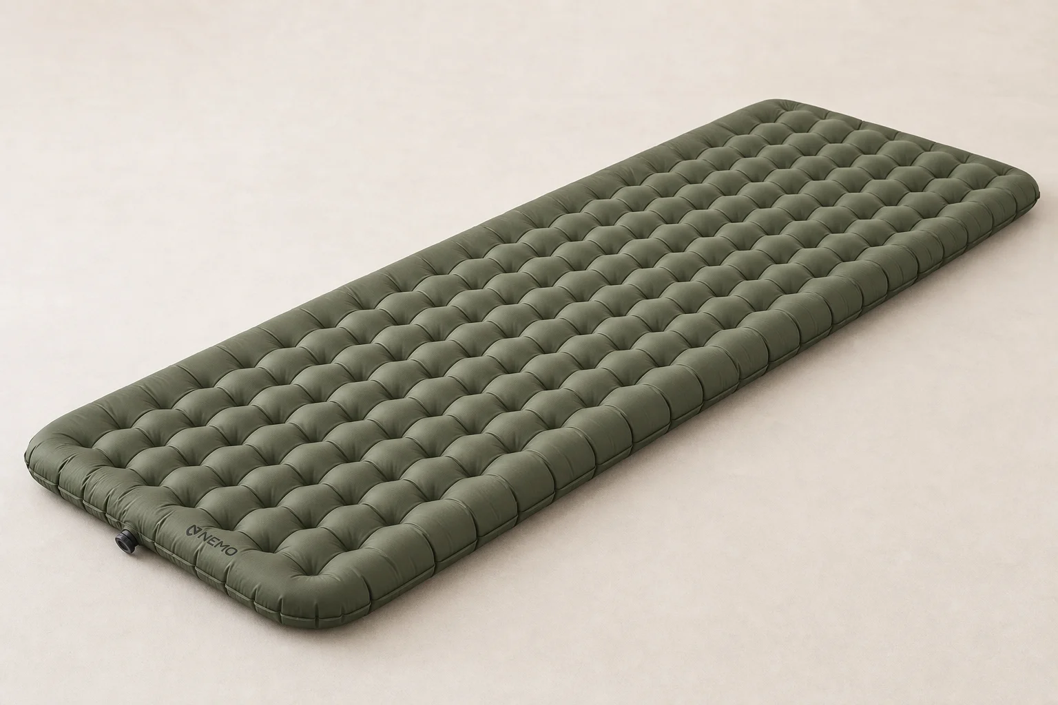 Siete colchonetas de dormir dispuestas sobre una superficie de hormigón que muestran la gama desde opciones ultraligeras hasta de longitud completa