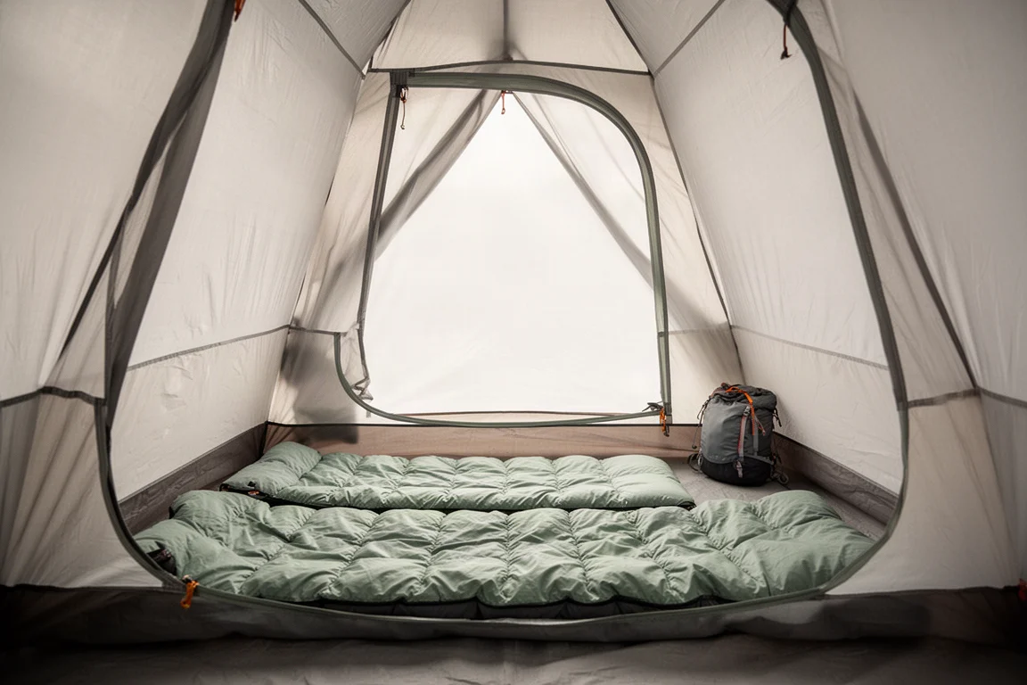 Interior of a two-person tent with sleeping pad, quilt, and gear bag in daylight