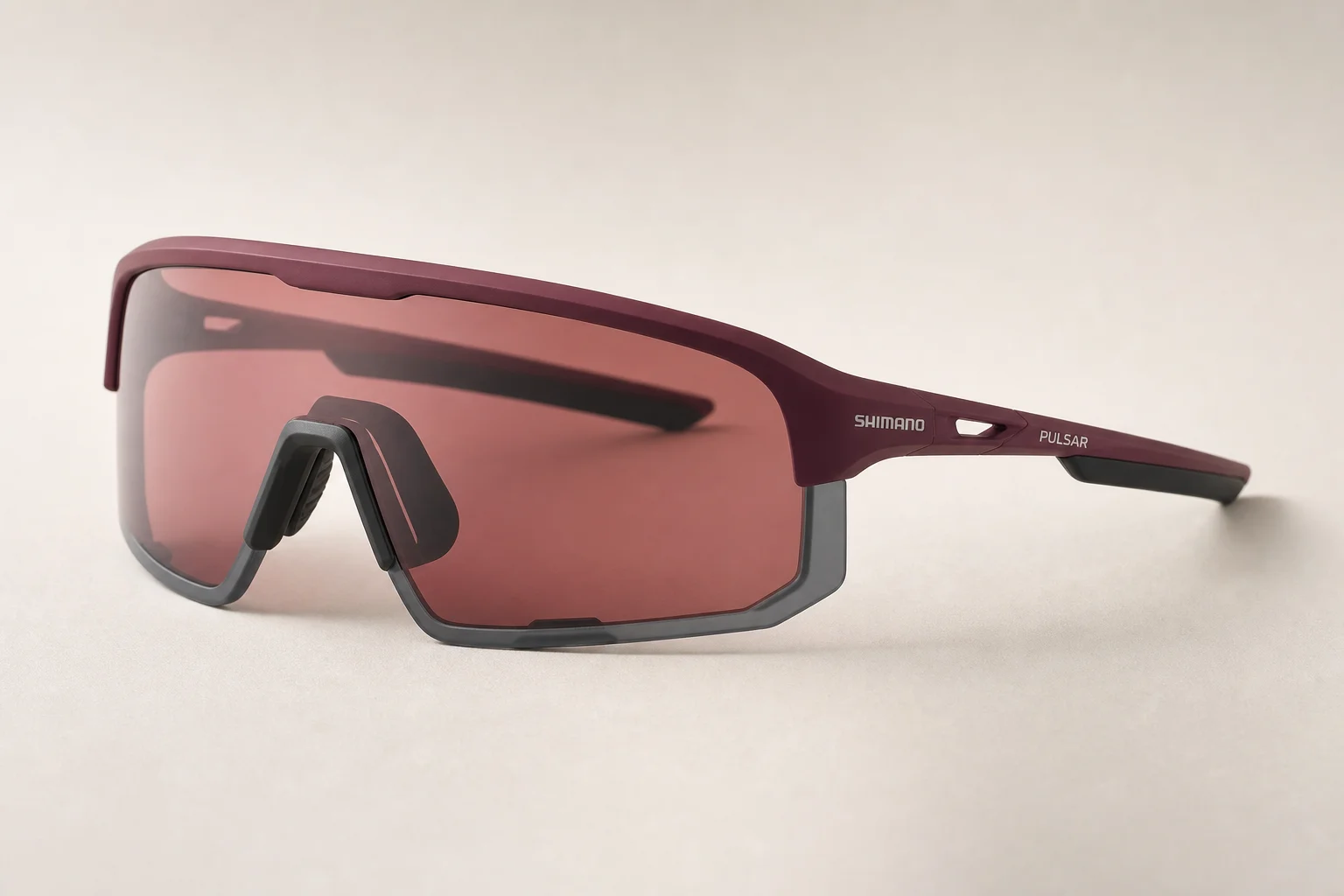 Shimano Pulsar cycling sunglasses in teaberry color on neutral backdrop