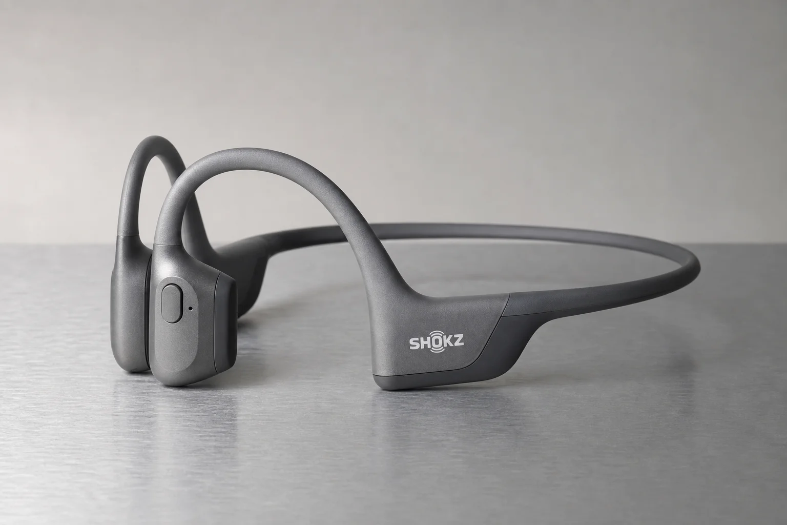 Six bone conduction headphones arranged on concrete surface showing different models and designs