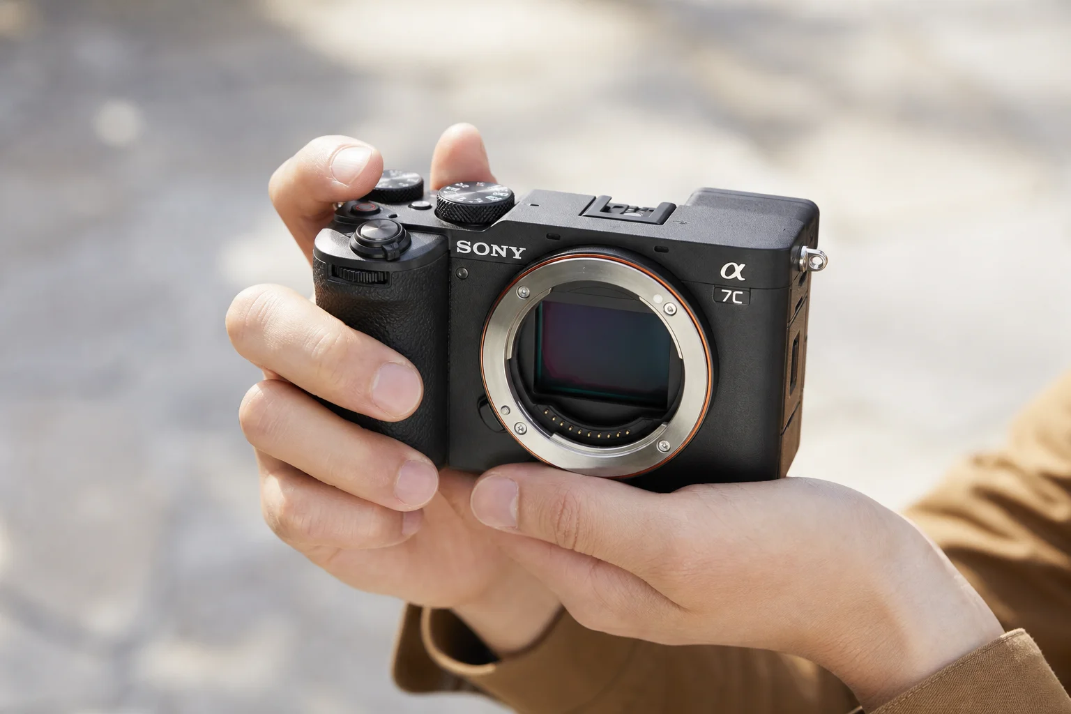 Photographer's hands holding a compact camera in daylight