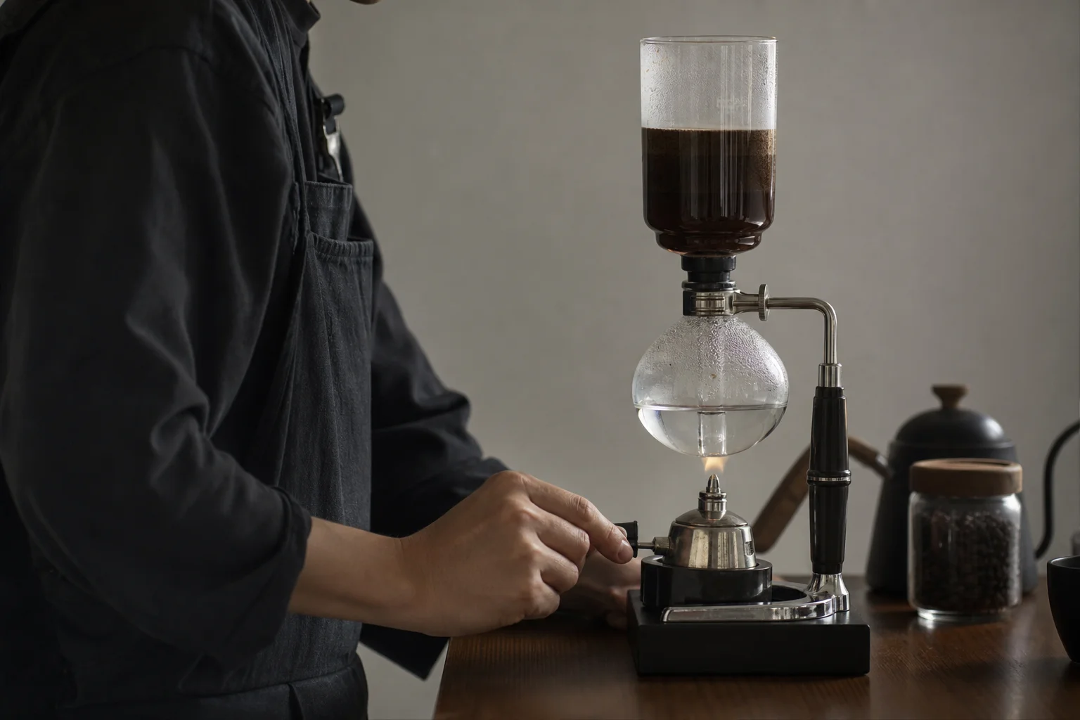 Barista performing siphon brewing technique with focused concentration