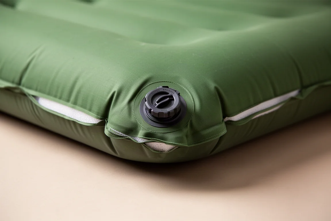 Close-up of a twist-lock air valve on the corner of a green sleeping pad