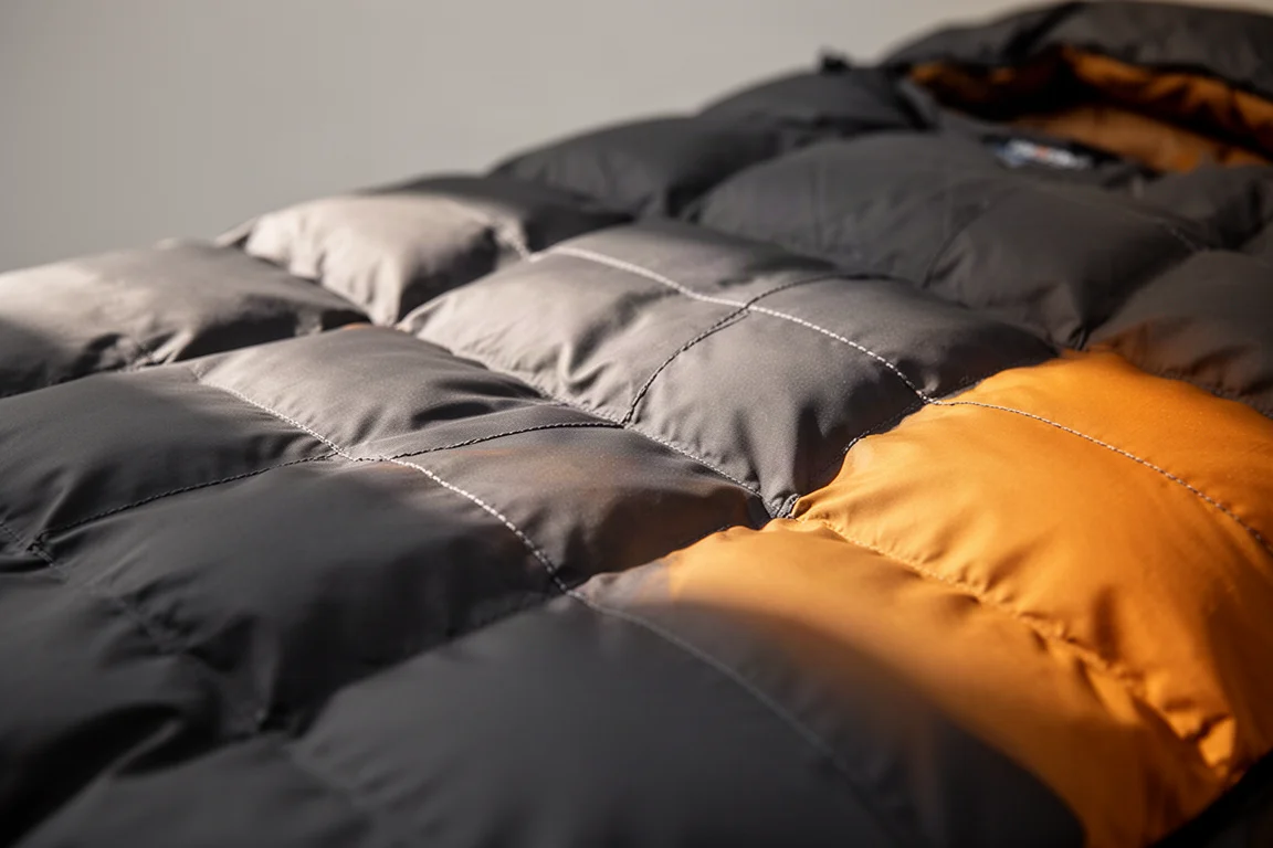 Primer plano de los tabiques de plumón y las costuras de la cubierta de un saco de dormir