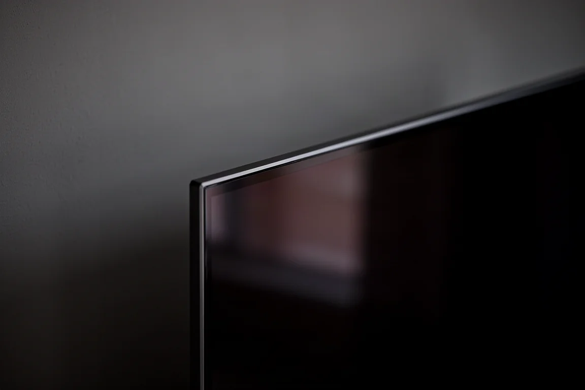 Närbild av en tunn OLED-TV-kant i ett mörkt rum med svag skärmreflektion