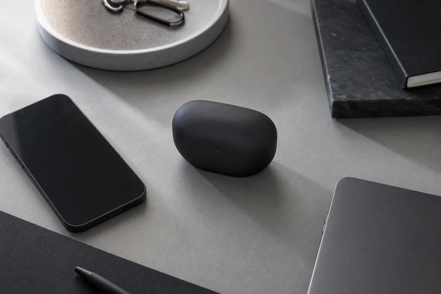 Wireless earbuds charging case on a desk with tech accessories