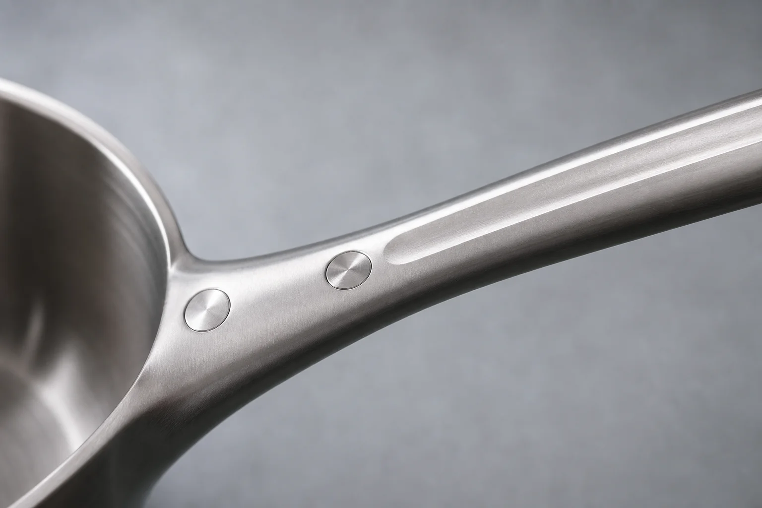 Primer plano del mango de un utensilio de cocina que muestra remaches al ras y un diseño que disipa el calor