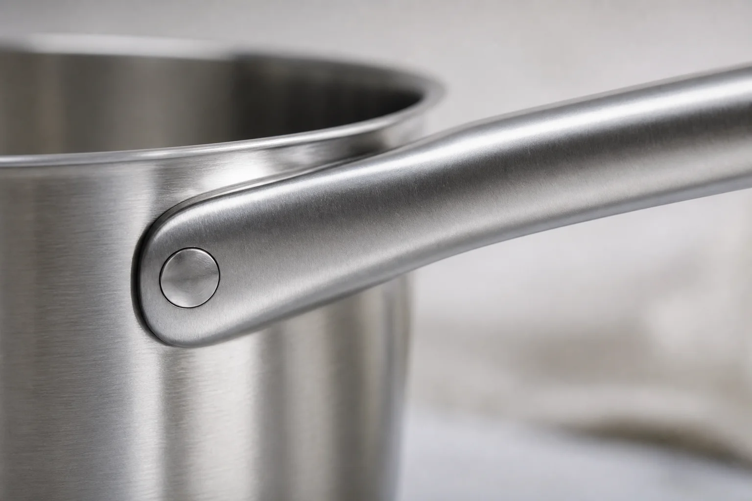 Close-up of stainless steel pan handle with flush rivets and heat-dispersing groove