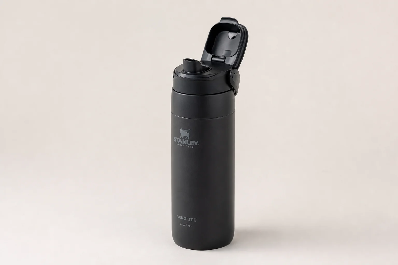 Nine insulated travel mugs arranged on concrete surface in various styles and colors