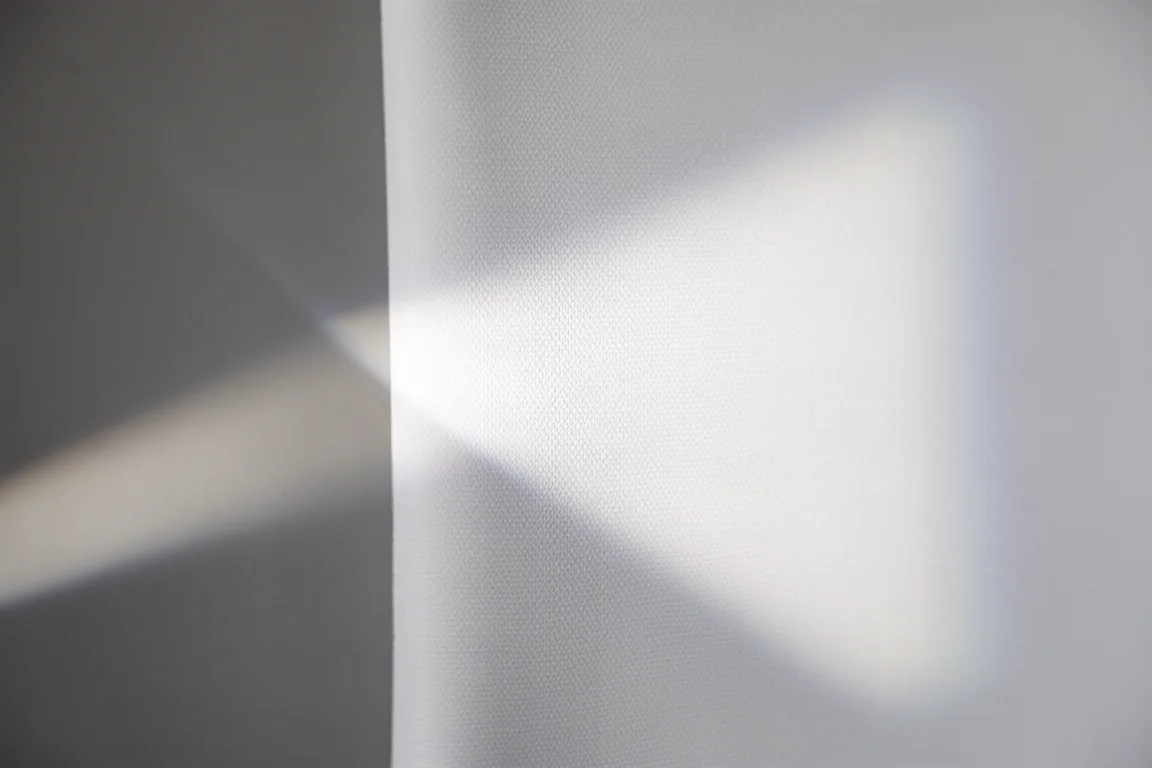 Close-up of stretched matte white projection screen fabric with light grazing the surface