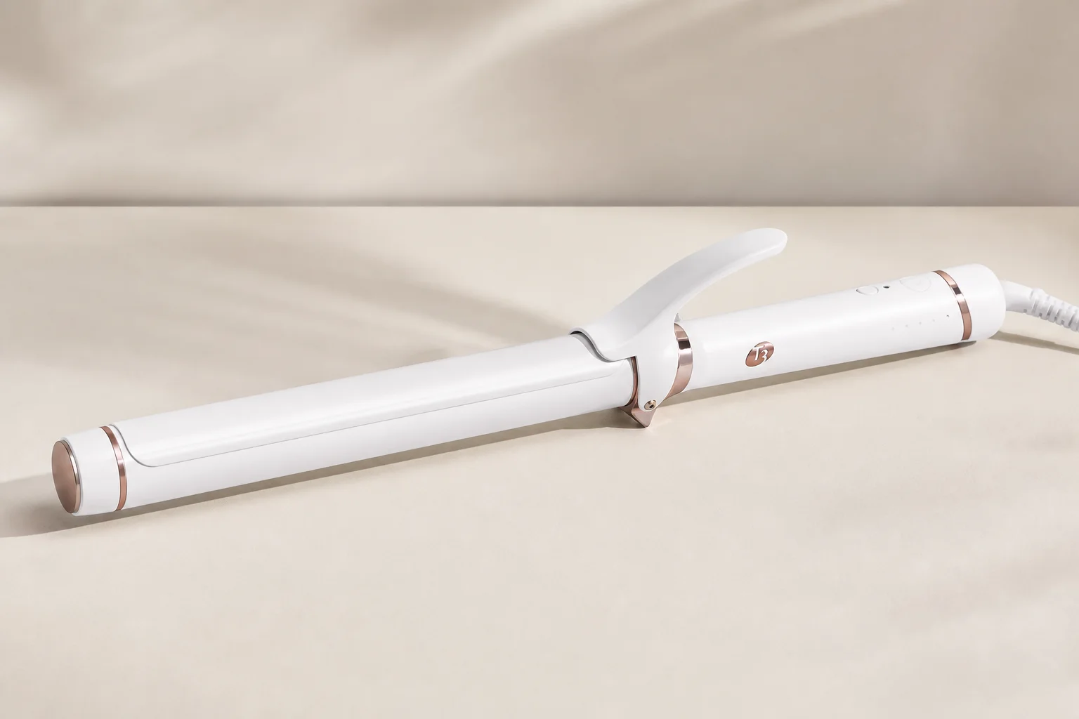 Five curling irons in various sizes arranged on a marble surface