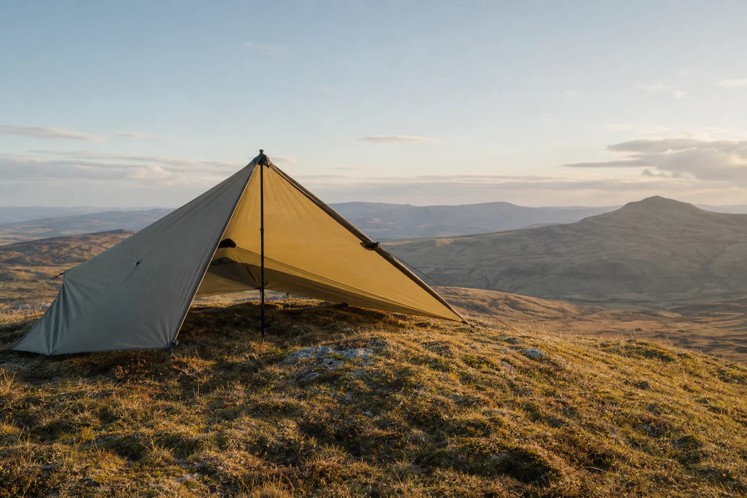 Tarp shelter pitched in moorland with open front facing landscape