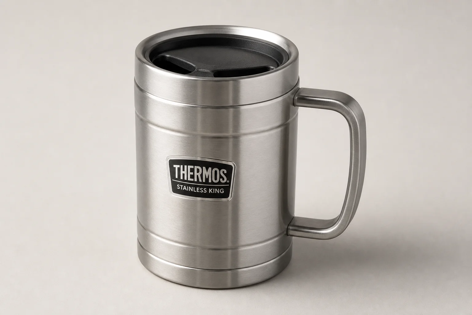 Nine insulated travel mugs arranged on concrete surface in various styles and colors