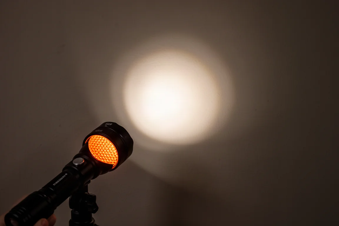 Handliche Taschenlampe projiziert einen hellen zentralen Lichtfleck auf eine dunkle Wand