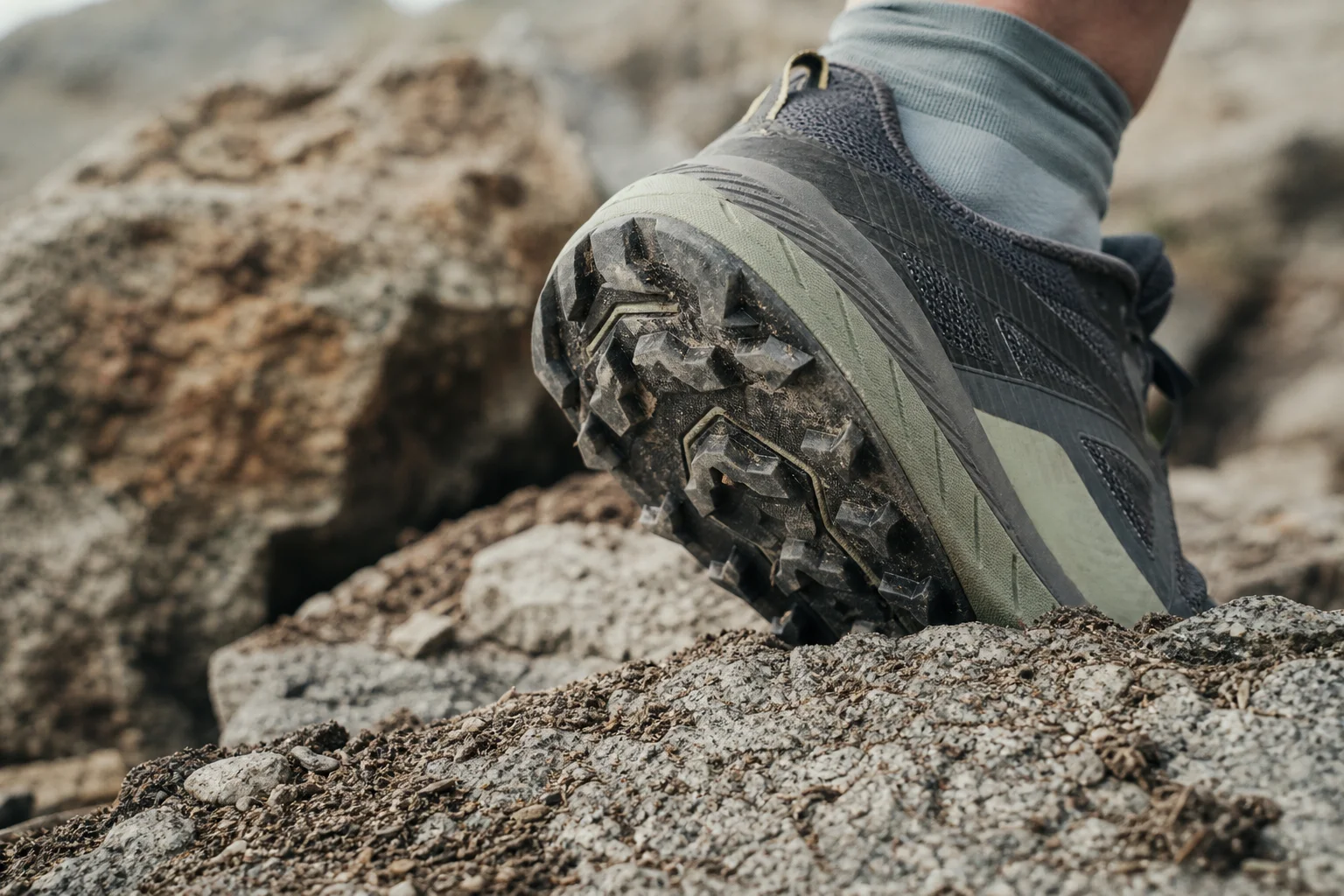 Gros plan sur la semelle d'une chaussure de trail sur un terrain technique rocheux